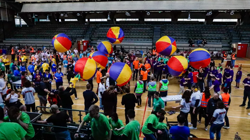 Eine große Menge an Menschen und viele große, bunte Bälle schweben über der Menge