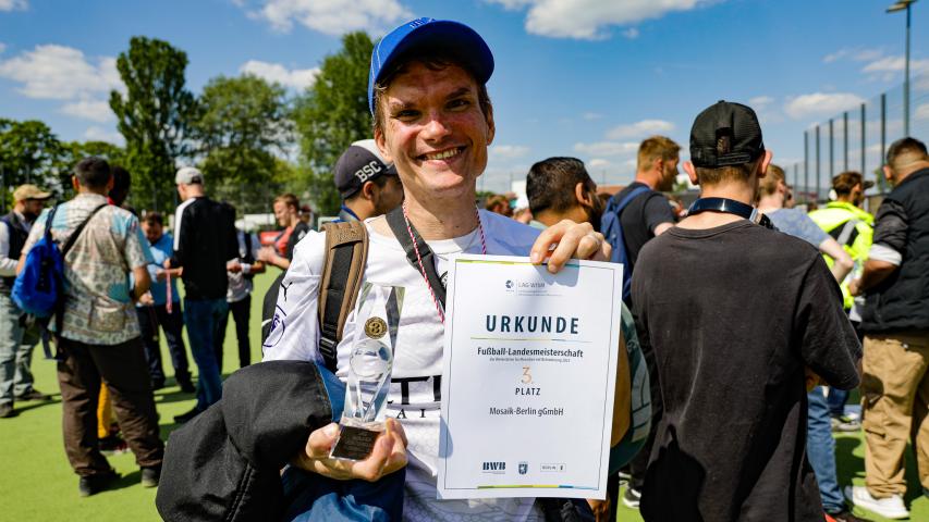 Mosaik Spieler hält Pokal und Urkunde
