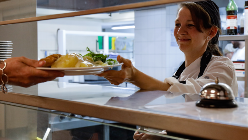 Mitarbeiterin bei der Essenausgabe in der Mosaik-Kantine Konzerthaus, Juni 2024